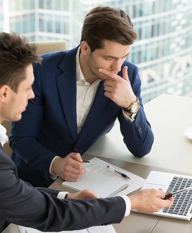 Two men in front of laptop and papers
